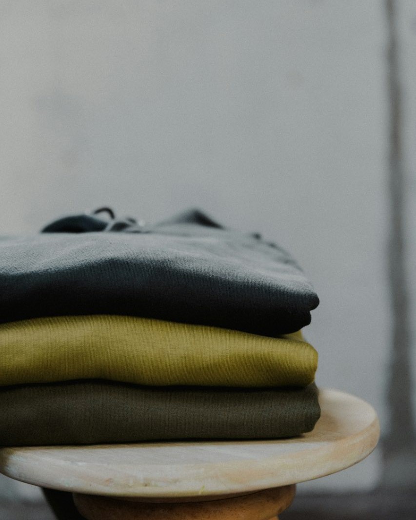 Folded henley shirts stacked on a wooden shelf