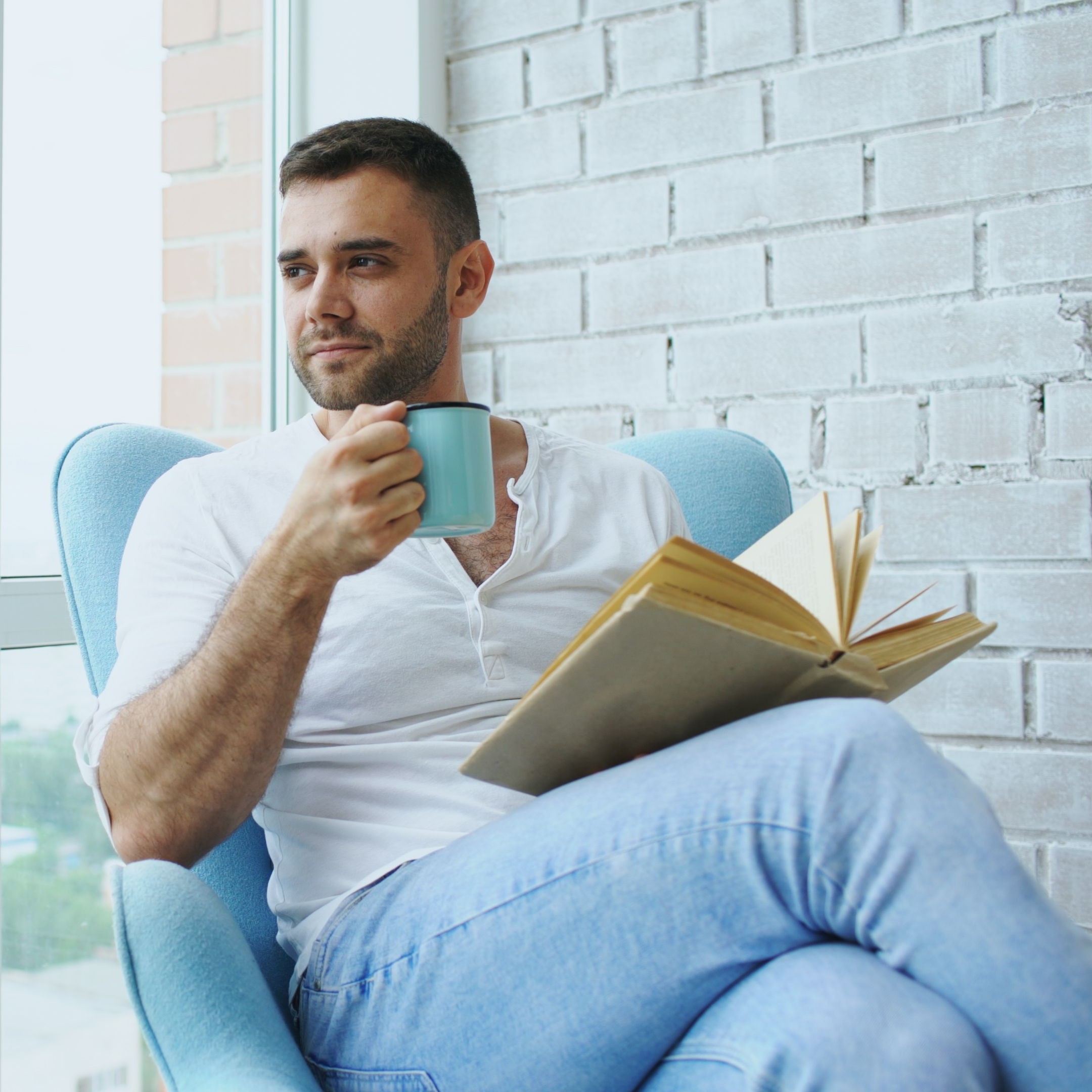 Man in a knit henley reading a book in a cafe
